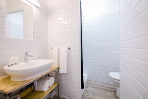 Un baño moderno con un lavamanos, espejo y retrete blancos.