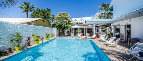 Una piscina al aire libre, sombrillas, sillones reclinables de piscina