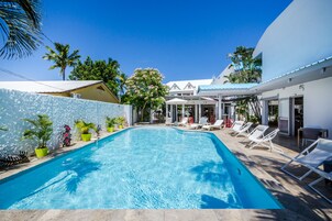 Una piscina al aire libre, sombrillas, sillones reclinables de piscina