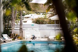 Una piscina al aire libre, sombrillas, sillones reclinables de piscina
