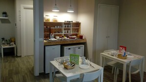 Eine kompakte Küche mit Essbereich, ausgestattet mit einem Kühlschrank, einer Kaffeemaschine und einem kleinen Spülbecken.
