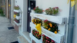 Eine Reihe weißer Gebäude mit Blumenkästen im Erdgeschoss, gefüllt mit bunten Blumen und gelben Bändern.