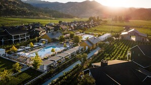 Ein Resort mit Schwimmbad, mehreren Gästehäusern und Weinbergen im Hintergrund.