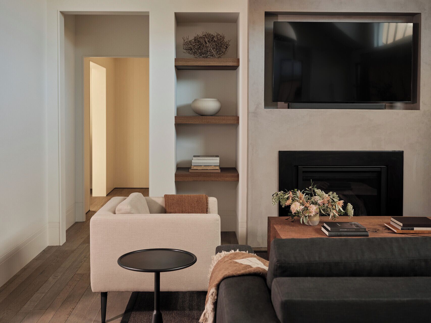 A modern living room with a sofa, a coffee table, a fireplace, and a television mounted on the wall.