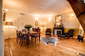 Un comedor con mesa y sillas de madera, alfombra de cebra y dos sillones de cuero.