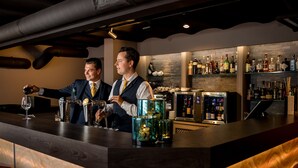 A bar area with two bartenders, a well-stocked liquor shelf, and a modern bar counter. - Kasteel de Wittenburg (Wassenaar)