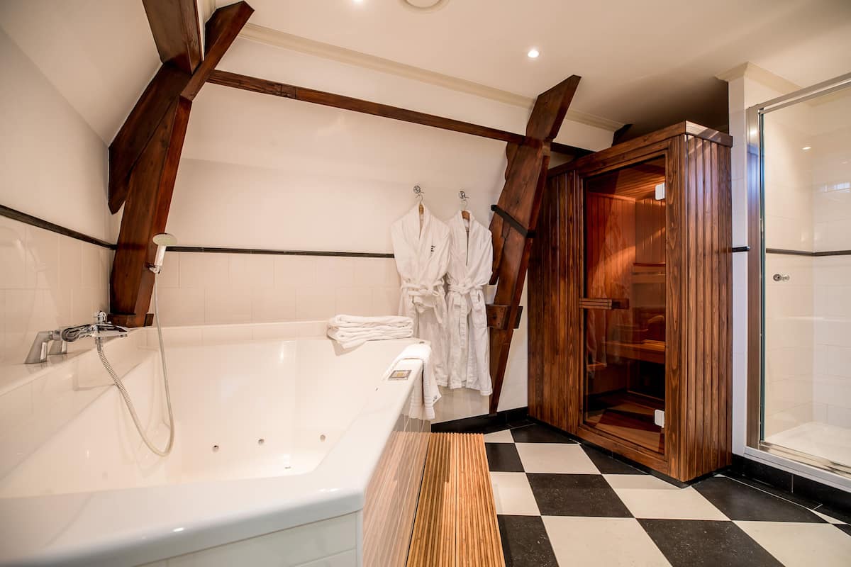 Une salle de bain moderne avec une grande baignoire, des poutres en bois et une cabine de douche en verre.