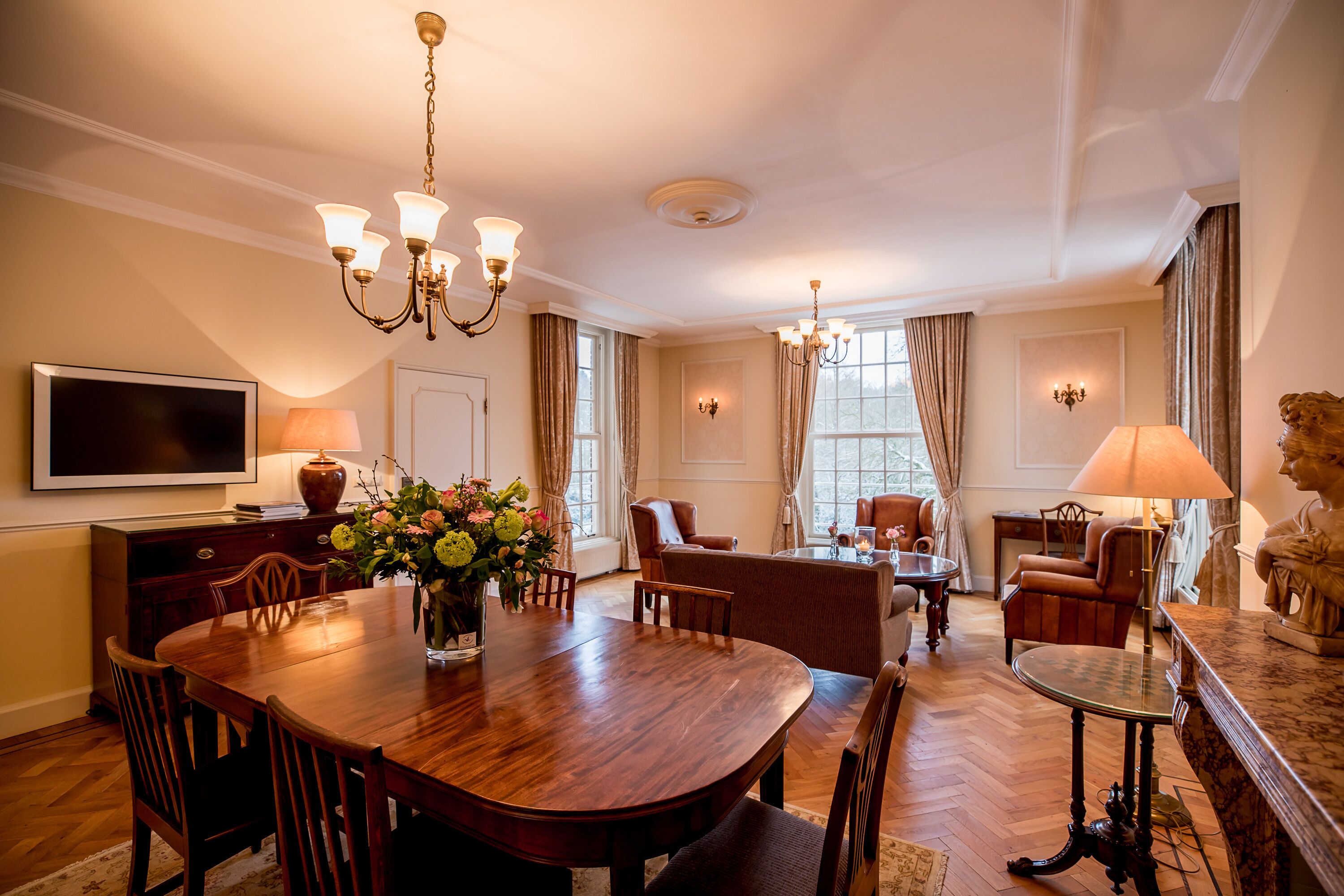 Une salle à manger spacieuse, dotée d’une grande table en bois, de nombreuses chaises et d’élégants lustres.