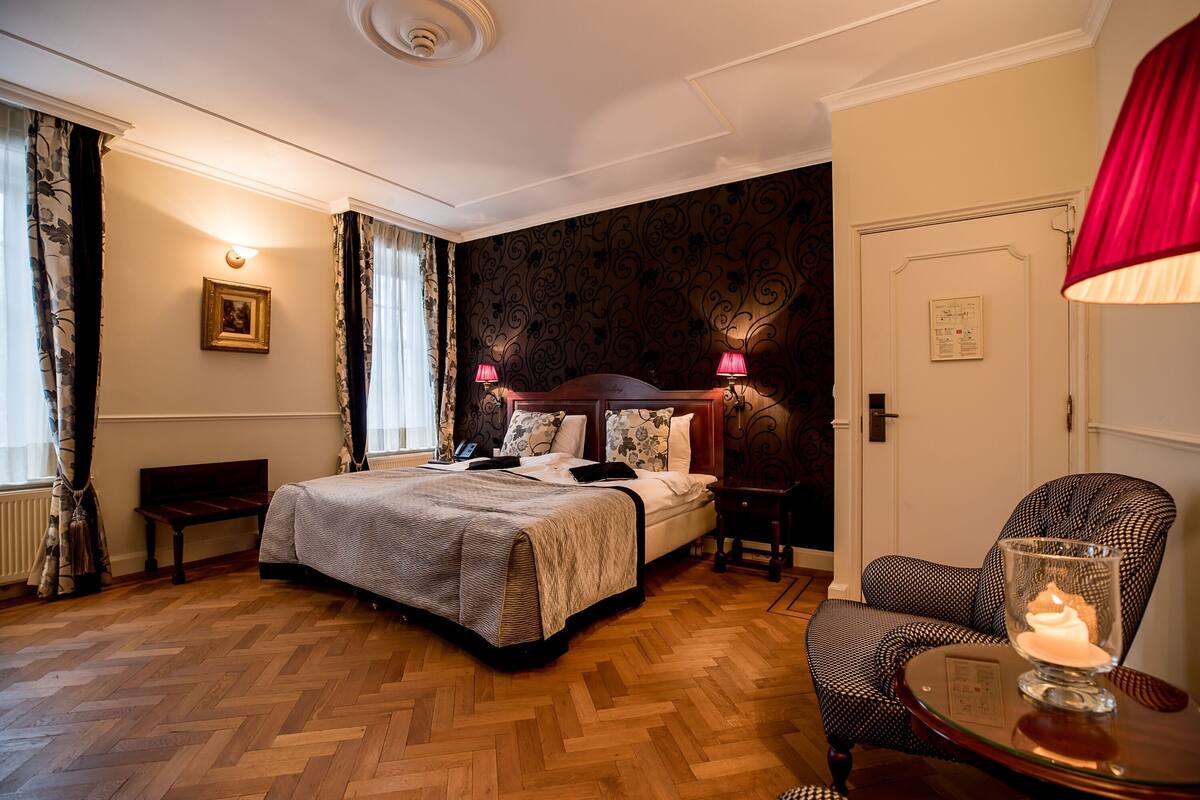 Une chambre d’hôtel avec un lit, une chaise, une table et une lampe.