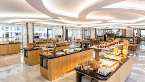 Moderni hotellin aula, jossa on avara pohjaratkaisu, keskeisellä paikalla sijaitseva buffet-alue ja baari.