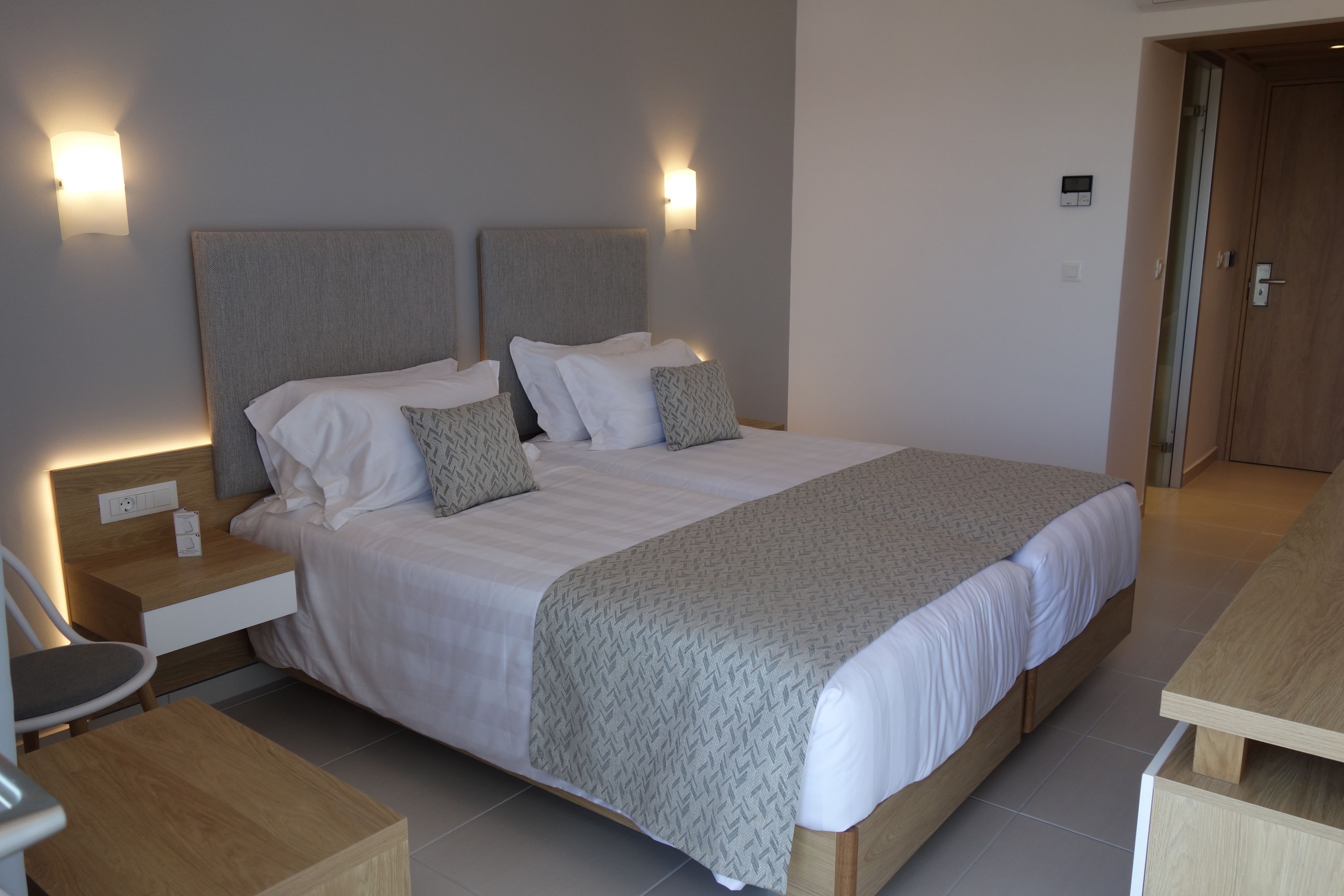 Ein modernes Hotelzimmer mit einem großen Bett, Nachttischen und Wandleuchten.