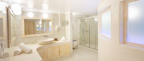 A modern bathroom with a large mirror, a round sink, a shower enclosure, and a toilet.