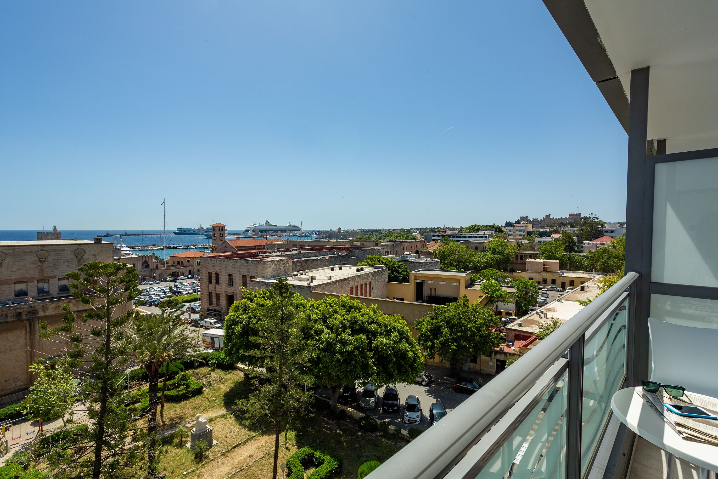 A balcony with a view of a marina, buildings, and greenery.