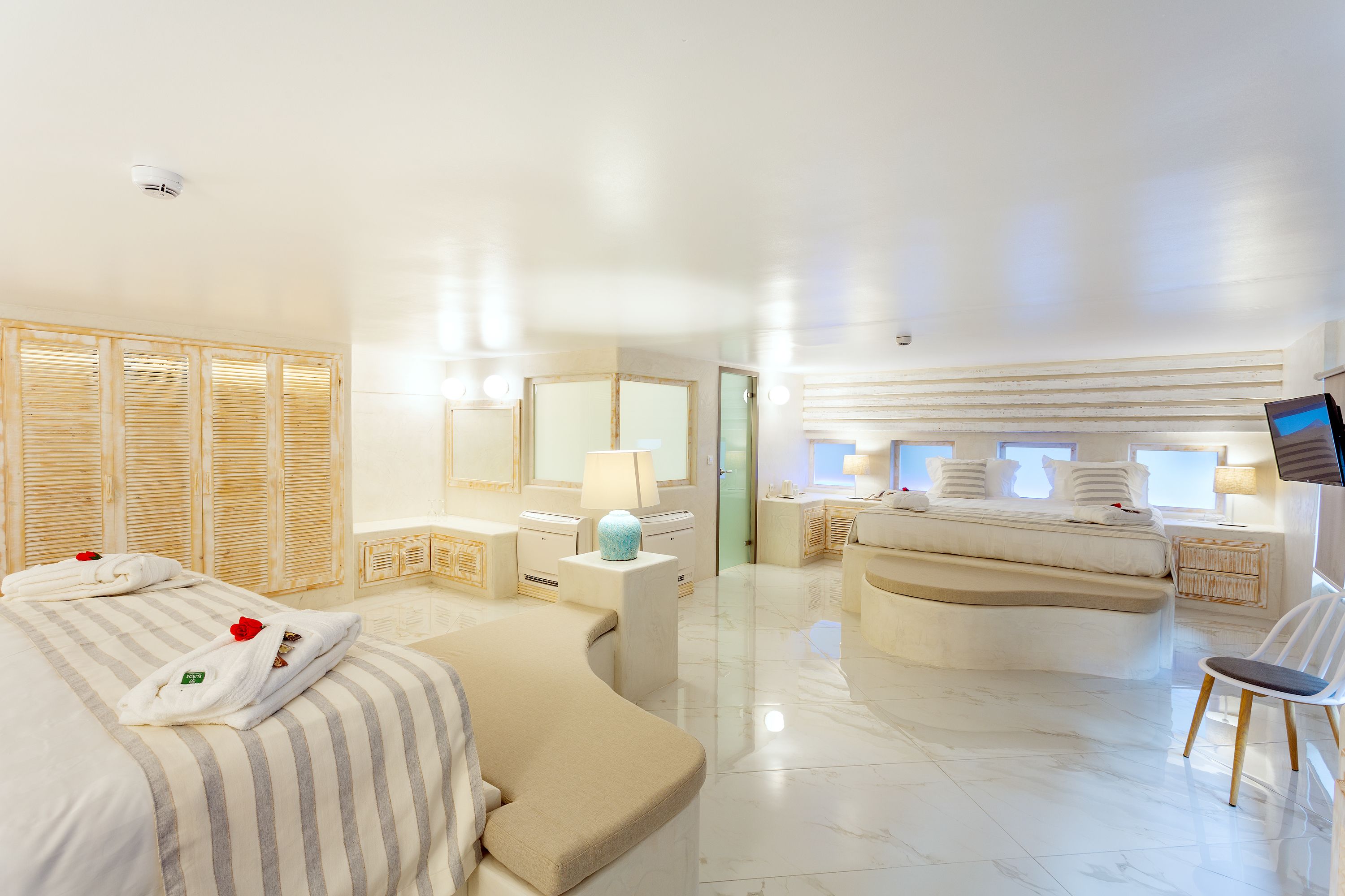 Une chambre d’hôtel moderne dotée d’un grand lit, d’un coin salon, d’une télévision et d’une salle de bain avec douche et toilettes.