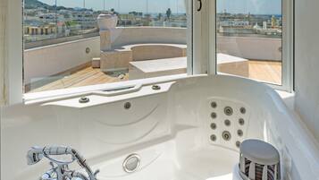 A modern bathroom with a large bathtub, a glass-enclosed shower area, and a view of the cityscape through large windows.