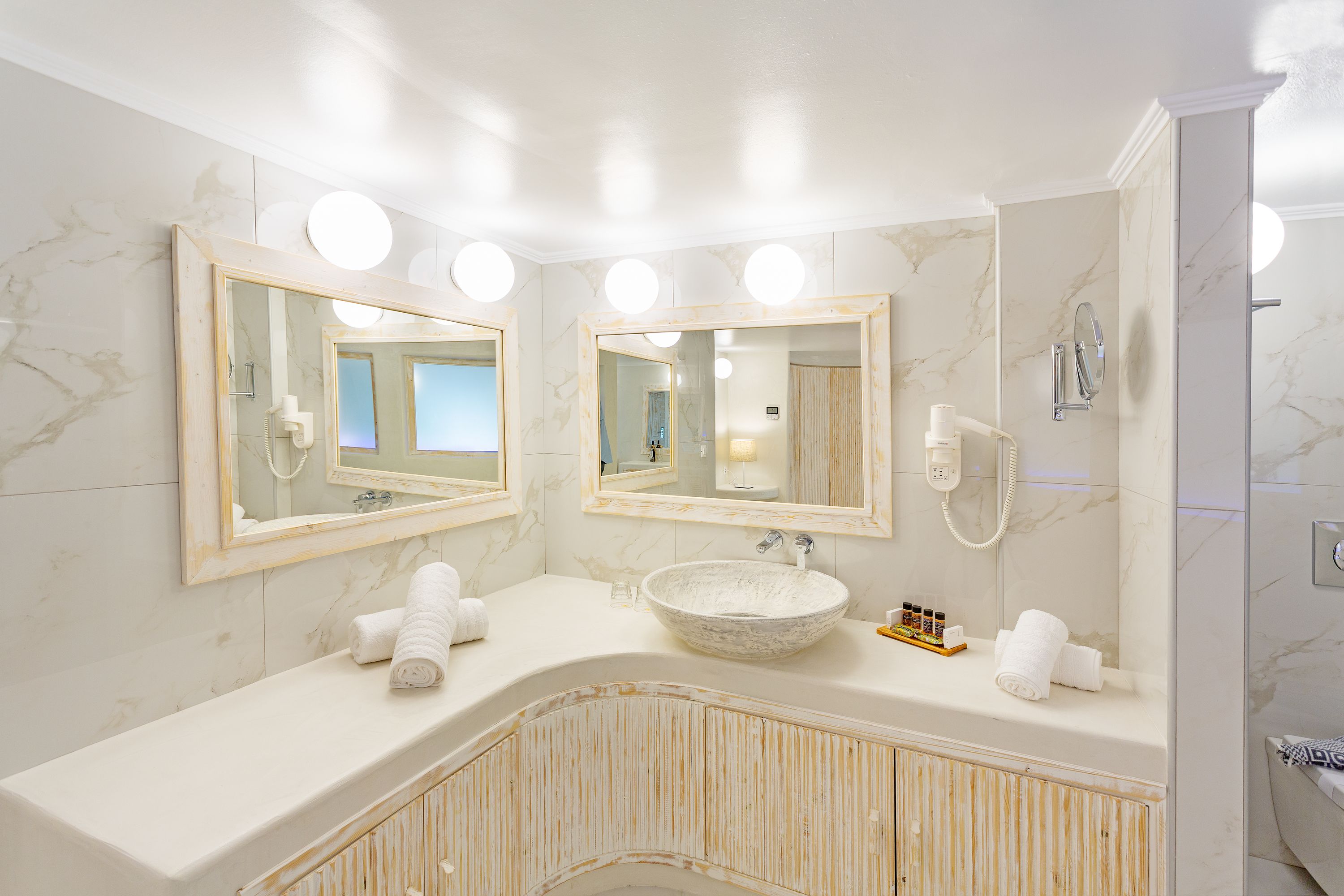 A bathroom with two large mirrors, a marble sink, and a shower.