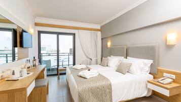 A modern hotel room with a large bed, a desk, a chair, and a view of the city through the window.