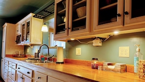 Una cocina con armarios de madera, un lavamanos y una encimera con diversos objetos.