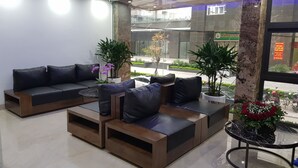 Um lobby moderno com um sofá seccional, uma mesinha e plantas em vasos.