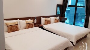 Quarto de hotel com duas camas, mesa de cabeceira, janela com cortinas e vista para o exterior.