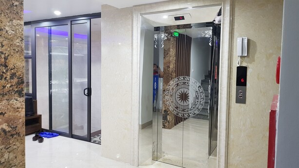 Um elevador com mostrador digital, corrimão e porta estampada.