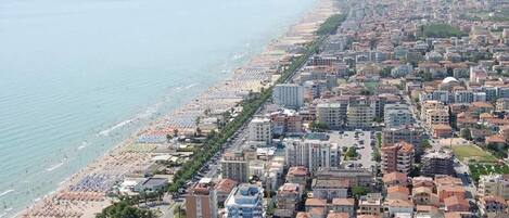 An aerial view of a coastal city with a beach, buildings, and a clear sky.