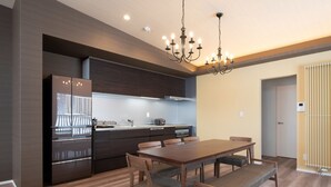 A modern kitchen with dark cabinetry, a stainless steel refrigerator, and a built-in oven. - Mountain Butterfly (Kutchan)