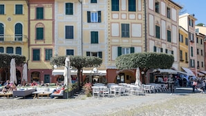A courtyard with outdoor seating, surrounded by multi-story buildings with balconies and shutters. - JOIVY La Finestra Sulla Piazzetta a Portofino (Portofino)