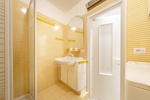 A bathroom with striped yellow walls, a white sink, and a mirror. - JOIVY La Finestra Sulla Piazzetta a Portofino (Portofino)