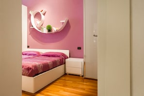Un dormitorio con cama, mesita de noche y estante en la pared con objetos decorativos.