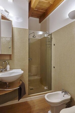 A bathroom with a glass-enclosed shower, a sink, and a bidet. - JOIVY Charming Apt Centre of Como (Como)