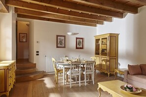 A dining area with a wooden table and chairs, a cabinet, and a sofa. - JOIVY Charming Apt Centre of Como (Como)