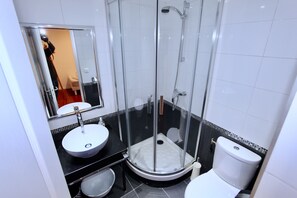 Et badeværelse med bruseniche, vask og toilet.