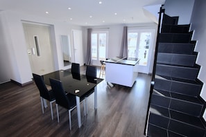 Une cuisine moderne avec un coin repas, un escalier et une vue sur l’extérieur.