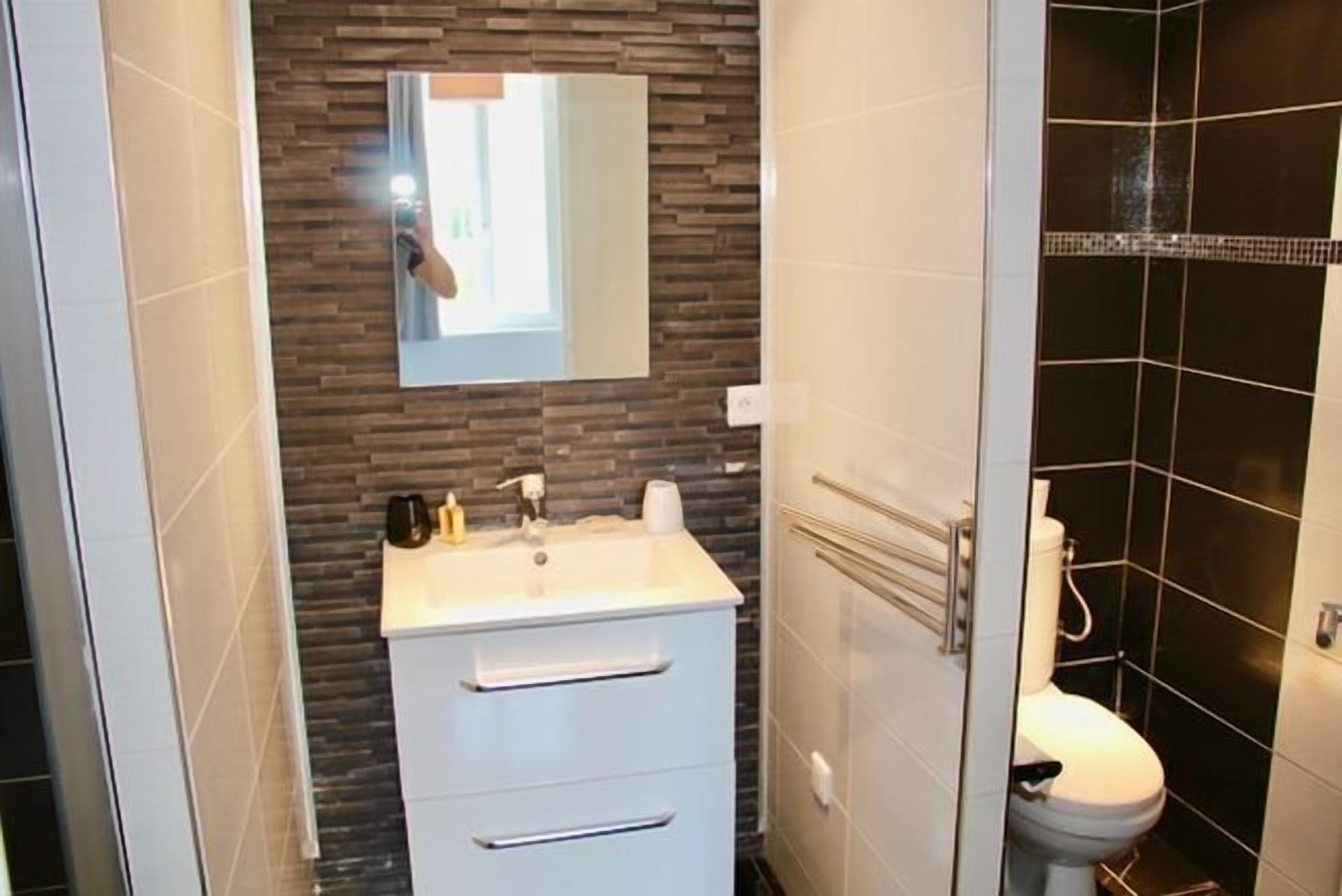 Une salle de bain avec un lavabo blanc, un miroir et des toilettes.