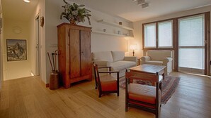 Una sala de estar con un aparador de madera, dos sofás, una mesa de centro y una lámpara.