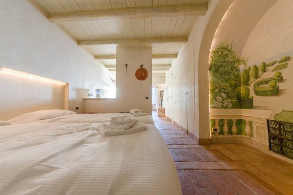 Habitación de hotel con dos camas, un pasillo y una pared decorada con plantas.