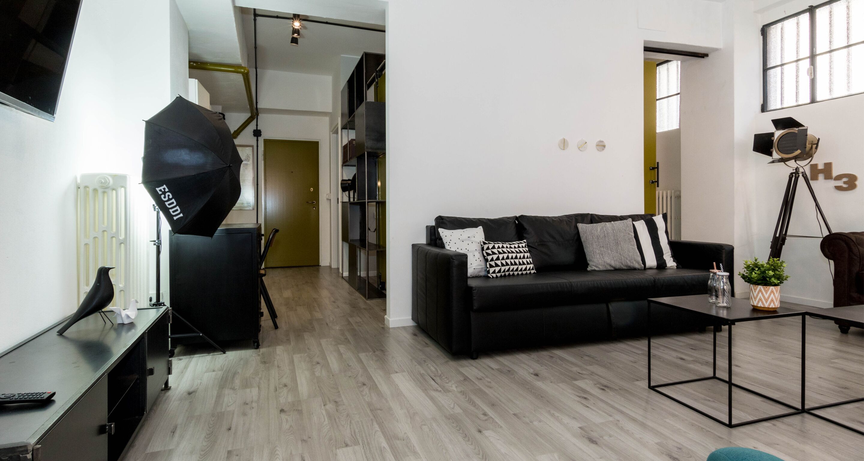 A modern living room with a black sofa, a coffee table, and a tripod with a camera on a tripod.