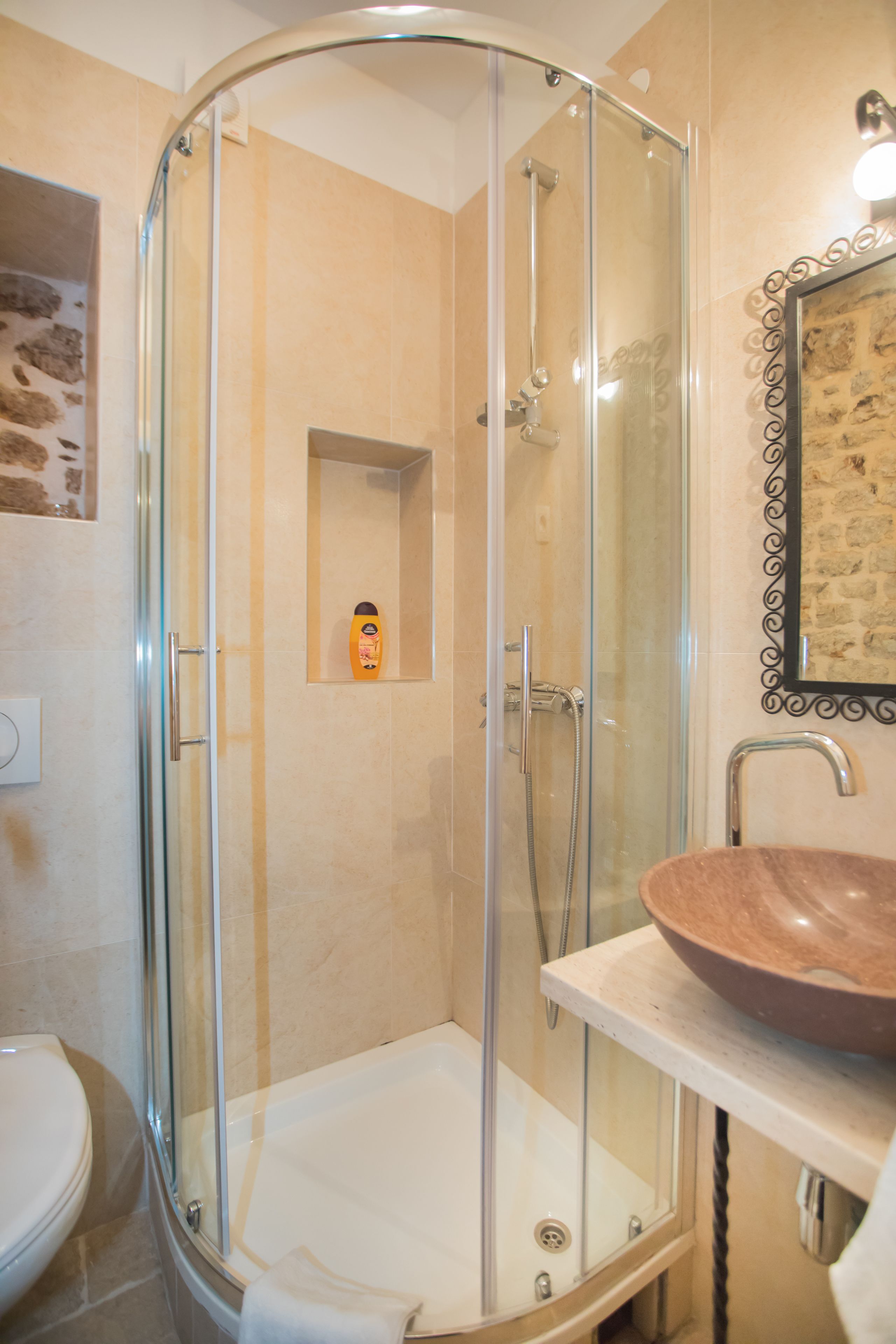 A glass-enclosed shower stall with a white sink and a framed picture on the wall.