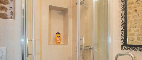 A glass-enclosed shower stall with a white sink and a framed picture on the wall.