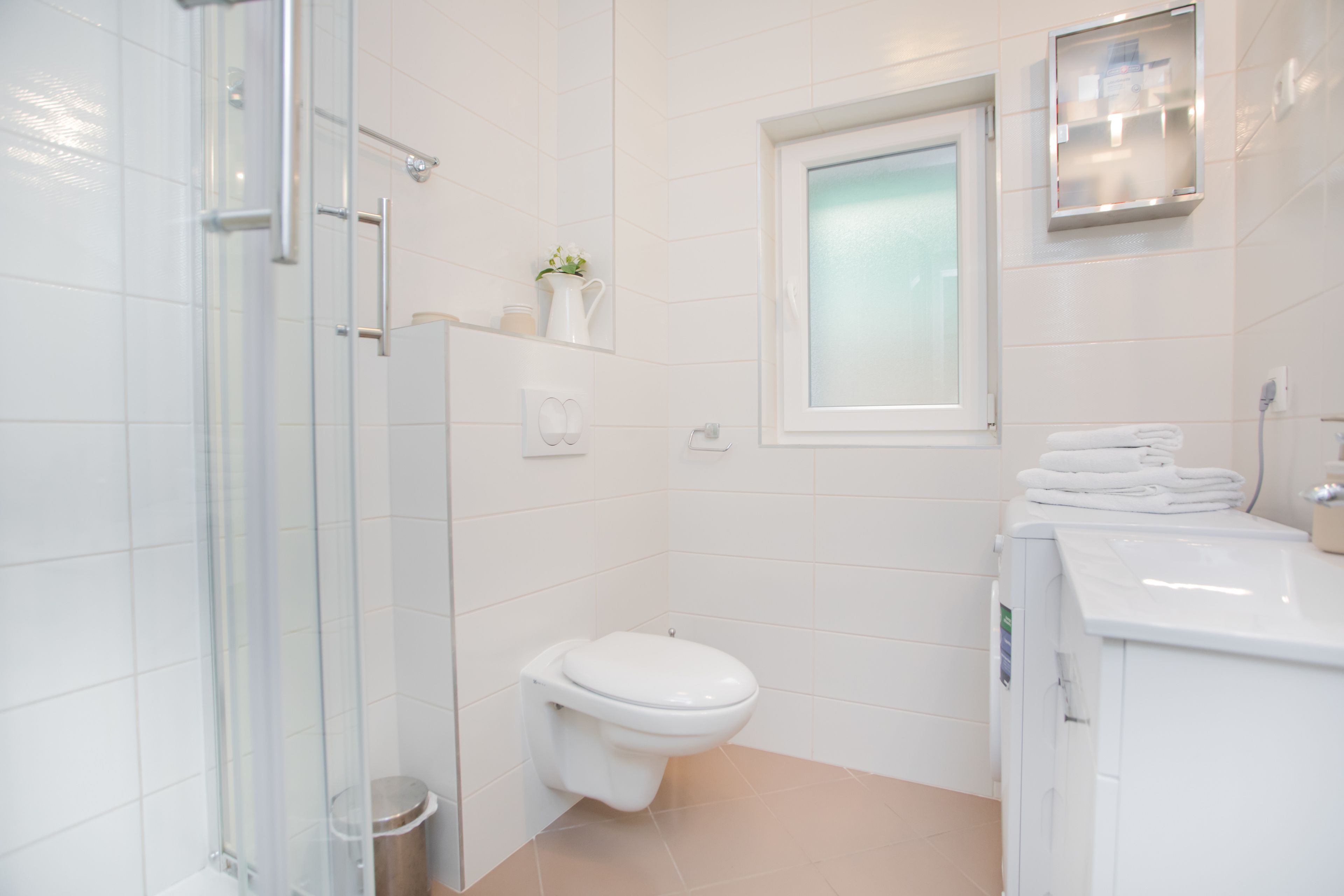 Un bagno moderno con box doccia in vetro, un water e una lavatrice integrata.