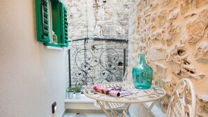 A small outdoor seating area with a round table, a green bottle, and a metal chair. - Residence Teatro - Near Cathedral of St James (Sibenik)