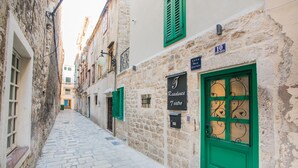 A narrow cobblestone street flanked by historic stone buildings with green shutters and a prominent green door. - Residence Teatro - Near Cathedral of St James (Sibenik)