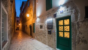A narrow cobblestone alley with stone buildings, a green door with a decorative window, and a sign indicating a restaurant. - Residence Teatro - Near Cathedral of St James (Sibenik)