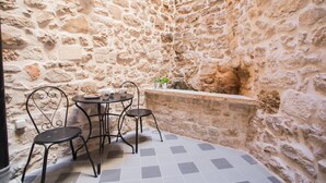 A stone-walled courtyard with a round table and four chairs. - Residence Teatro - Near Cathedral of St James (Sibenik)