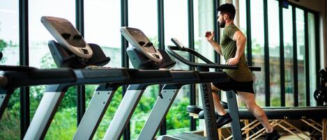 A gym with treadmills and a large window.