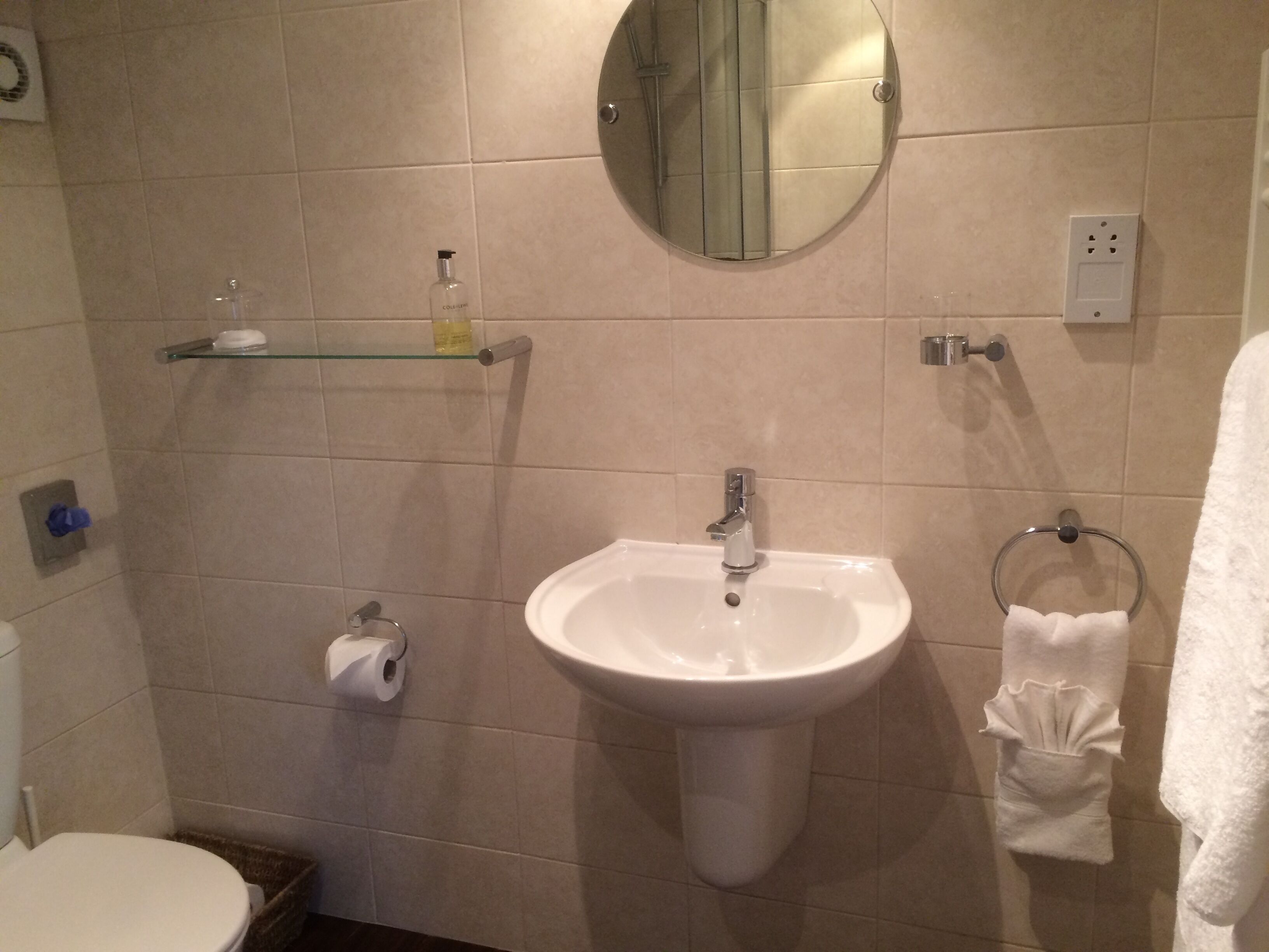 A bathroom with a white sink, a mirror, a toilet, and a towel rack.