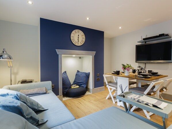 A modern bedroom with a bed, bedside table, lamp, and a wall clock.