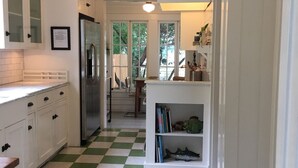A kitchen with white cabinets, a green and white checkered floor, a stainless steel refrigerator, and a bookshelf with books and decorative items. - Walk to Beach & Pleasure Pier - Lush Outdoor Entertaining (Galveston)