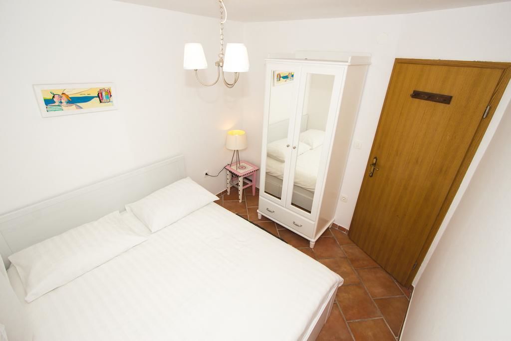 Une chambre à coucher comprenant un lit, une armoire, une table de chevet et une lampe fixée au mur.